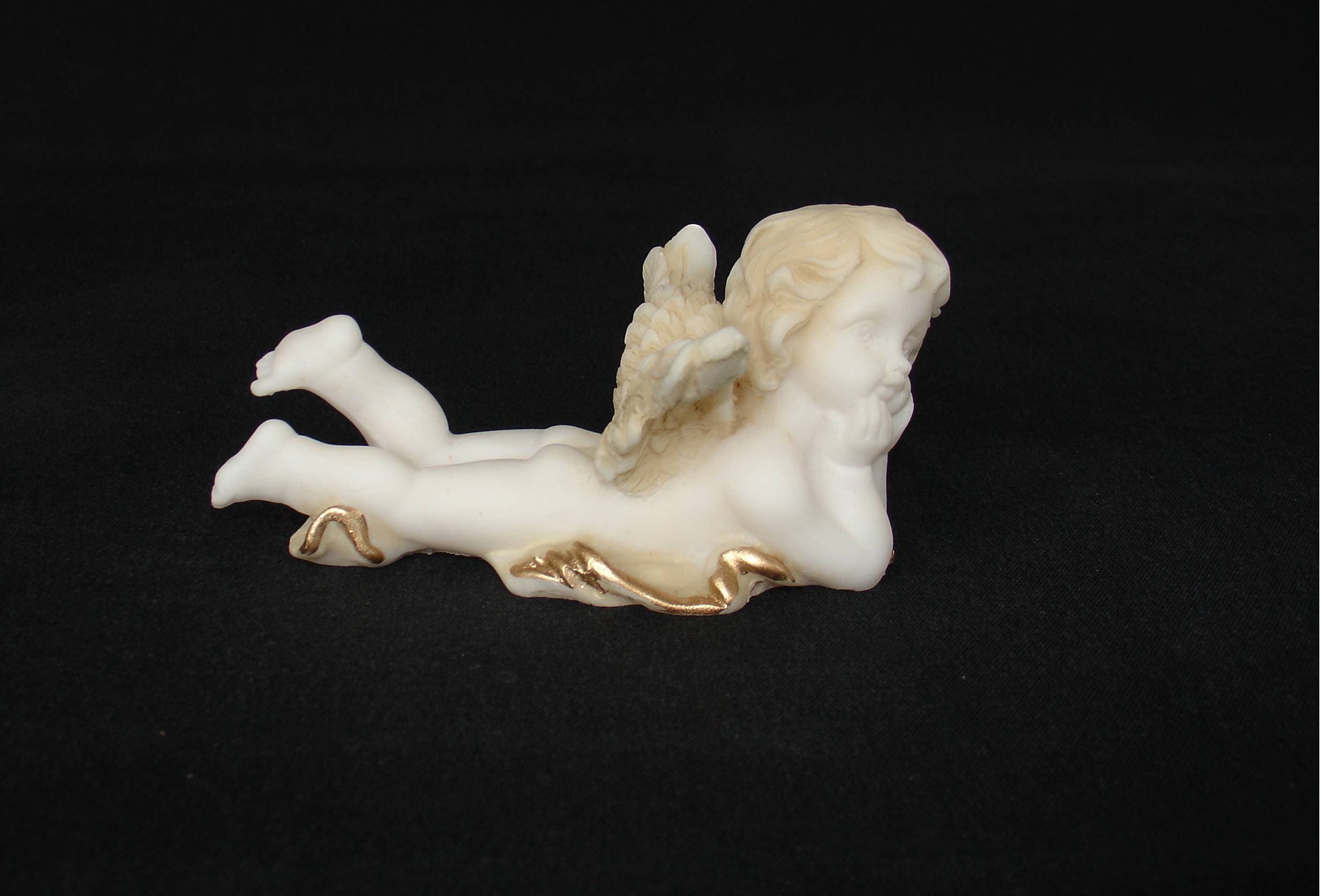 Lying angel holds his head statue
